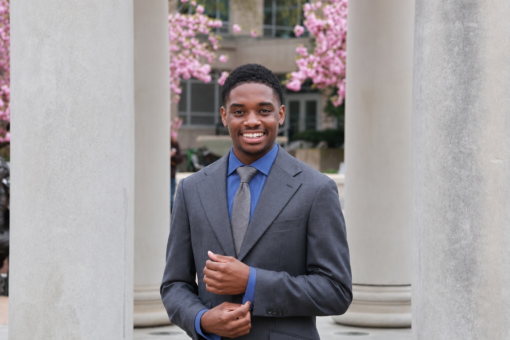 Alfred Lewis Jr., smiling in a grey suit jacket and blue dress shirt with a grey necktie